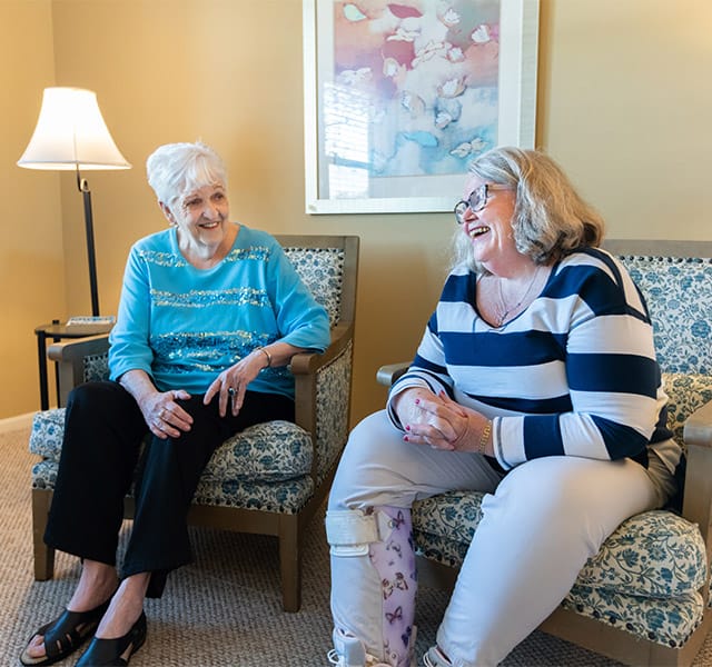 Female residents sitting on the couch laughing in a resident apartment