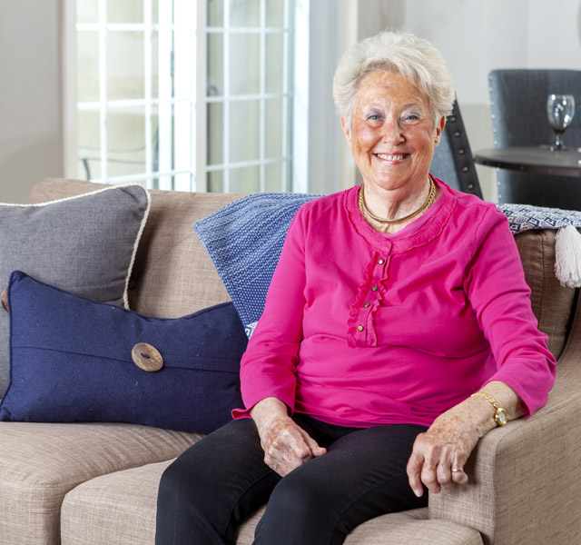 Independent living An elderly woman sitting on a cozy couch looking health and full of light
