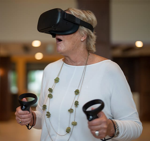 elderly woman with virtual reality goggles and controllers elderly woman with virtual reality goggles and controllers