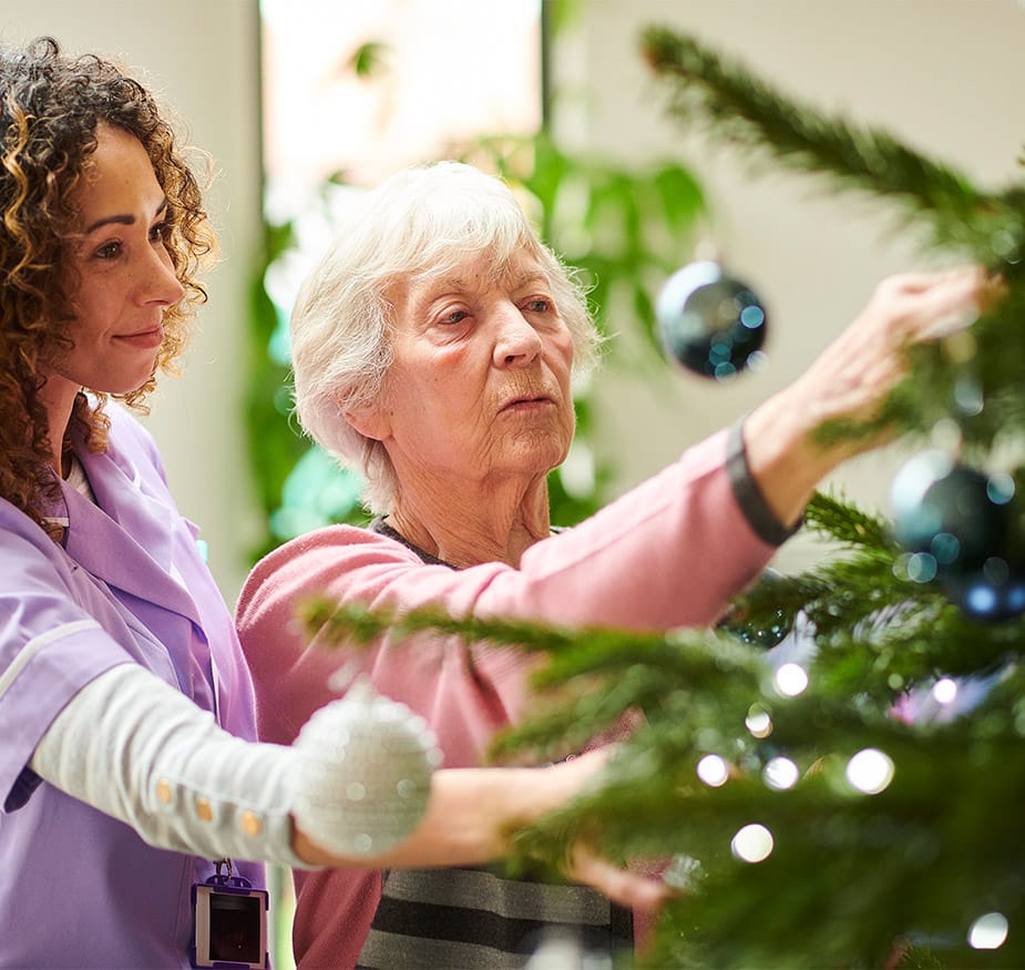 Amenities & Services Watermark at Home A resident decorating a tree for the holidays with a staff member
